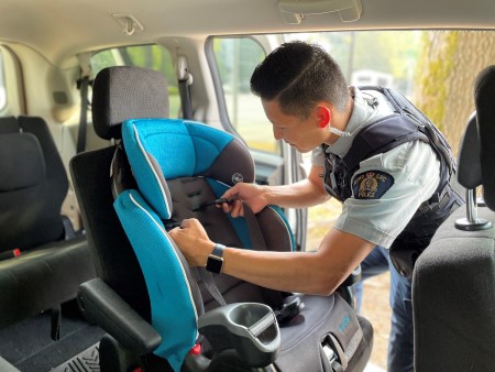 Interior view of a uniformed police officer inspecting a child seat in a vehicle