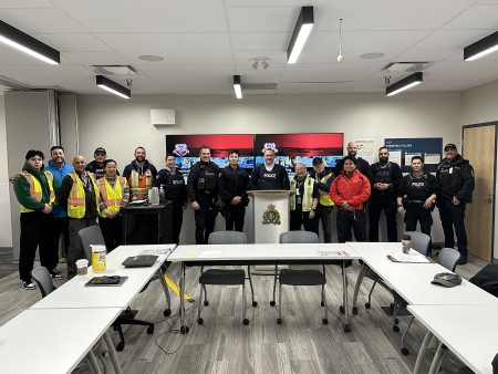 Group photo of Richmond RCMP officers, partner agencies, and volunteers standing together behind a table