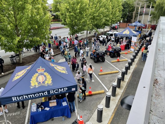 aerial of parking lot with Richmond RCMP booths set up and people gathered outside the community police office