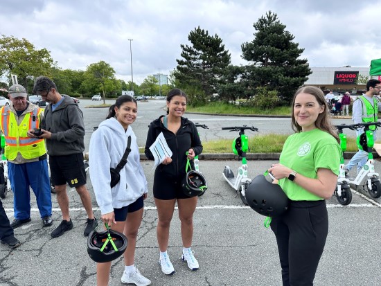 LIME team member standing with two event participants holding helmets