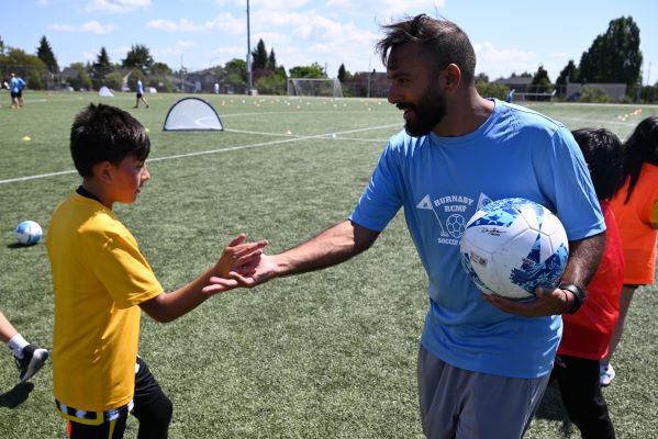 Des enfants souriant avec un ballon de soccer.