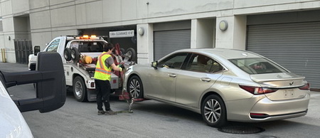 Vehicle attached to a tow truck with the tow truck driver standing next to it