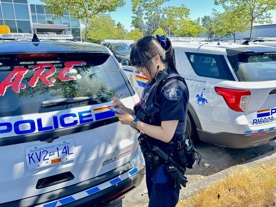 Constable Liu writing in her notepad in front of a police vehicle