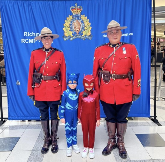 Police officers standing with two children who are wearing costumes