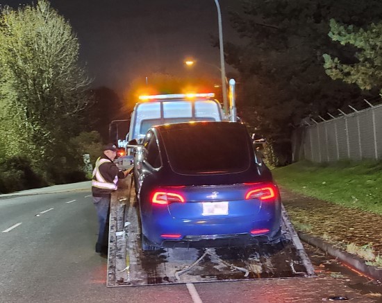 Blue car loaded onto a flat bed tow truck