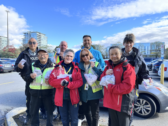 Richmond RCMP, volunteers, and community partners standing together holding pedestrian safety reflectors