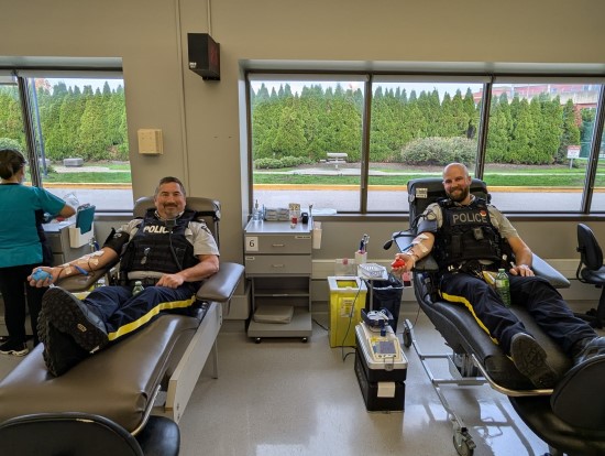 two Richmond RCMP officers sitting in chairs while donating blood